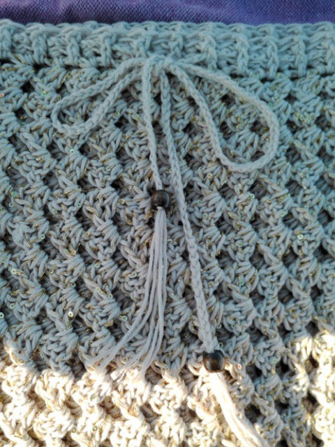 Close-up of a textured fabric with a tassel and beads.